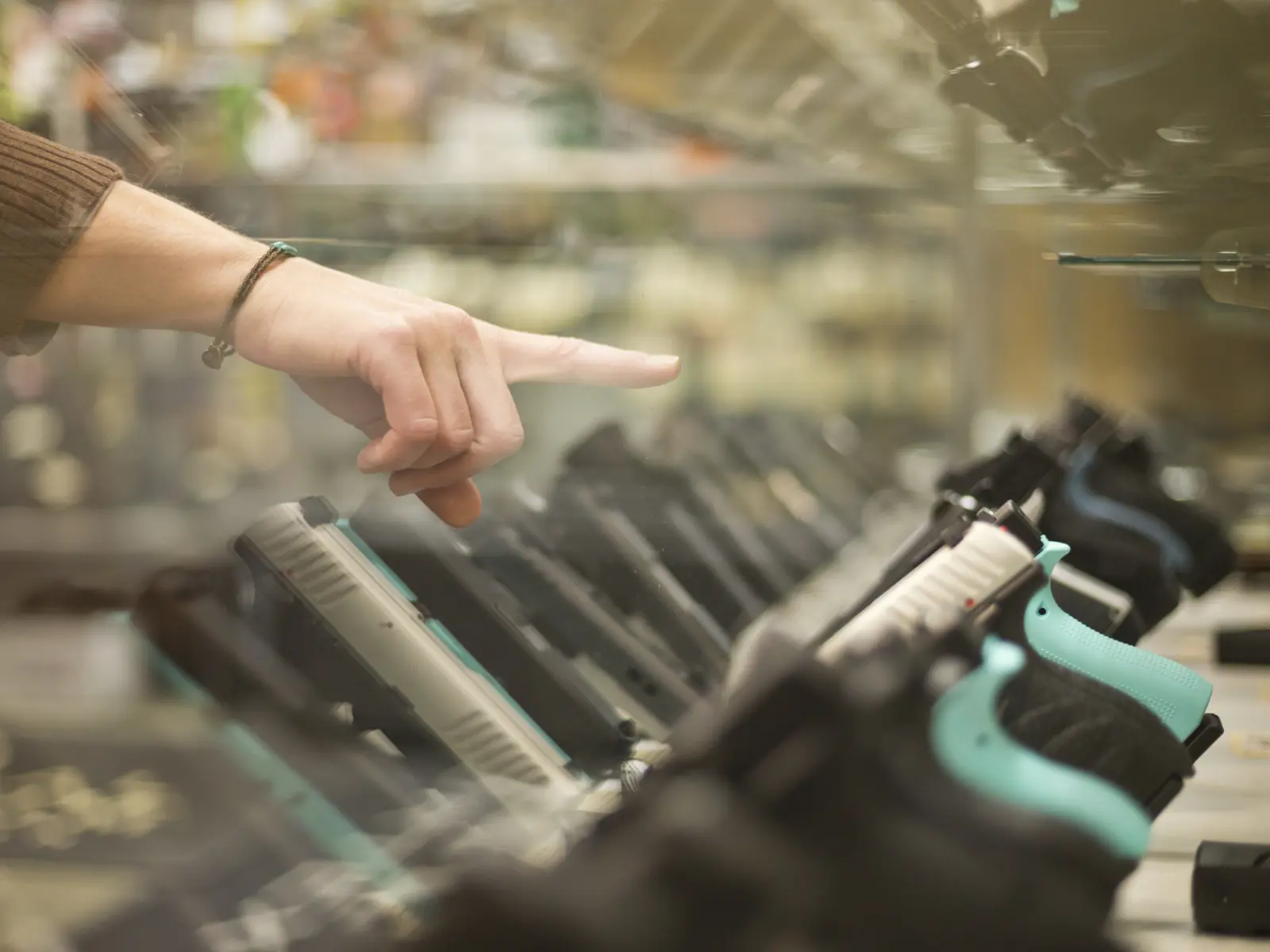 Customer pointing at hand gun through glass case.