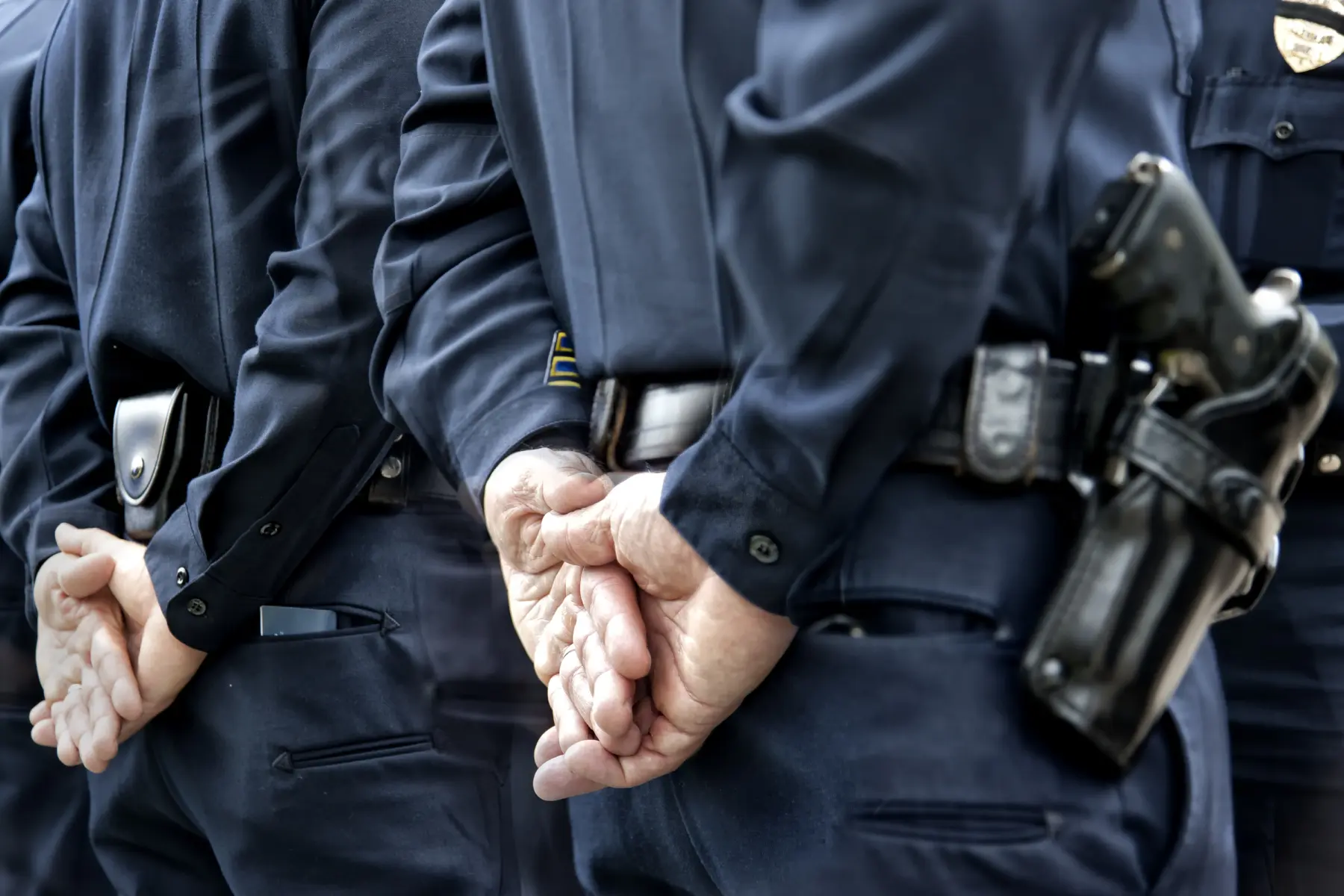 Rows of police officers in dark uniforms stand with hands clasped behind their backs.