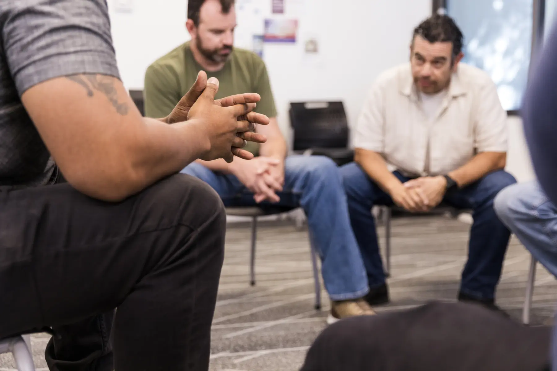 A group of four men seated in a circle, engaged in conversation.