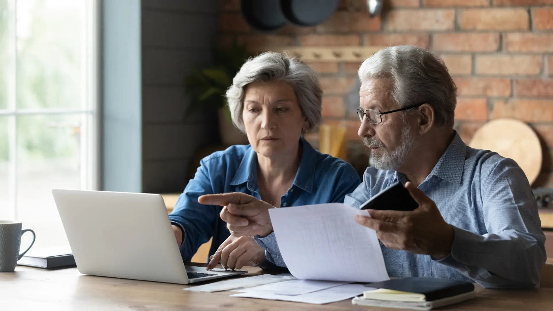 Man and women sitting at table paying their bills online.