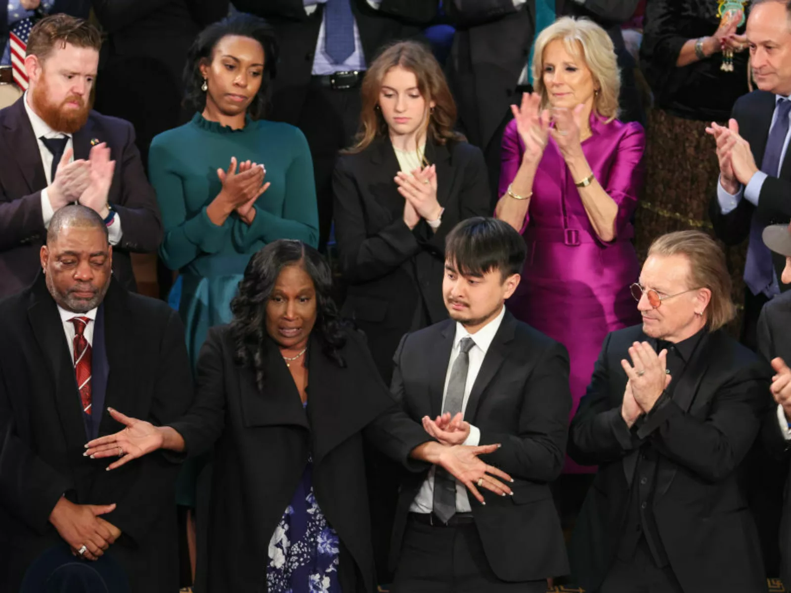 The parents of Tyre Nichols stand and are surrounded by people applauding.
