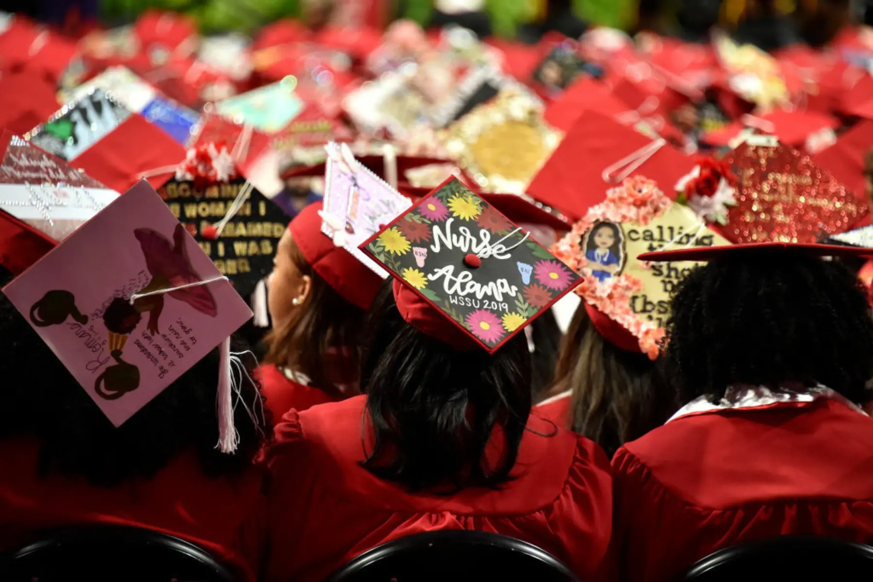 View of the backs of students and their decorated graduation caps at Winston-Salem State University commencement in 2019.