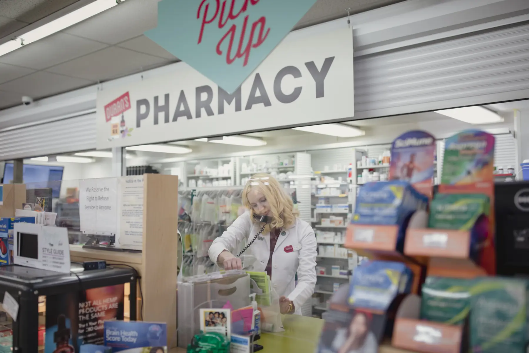 Pharmacist is seen behind the pharmacy window filling prescriptions.