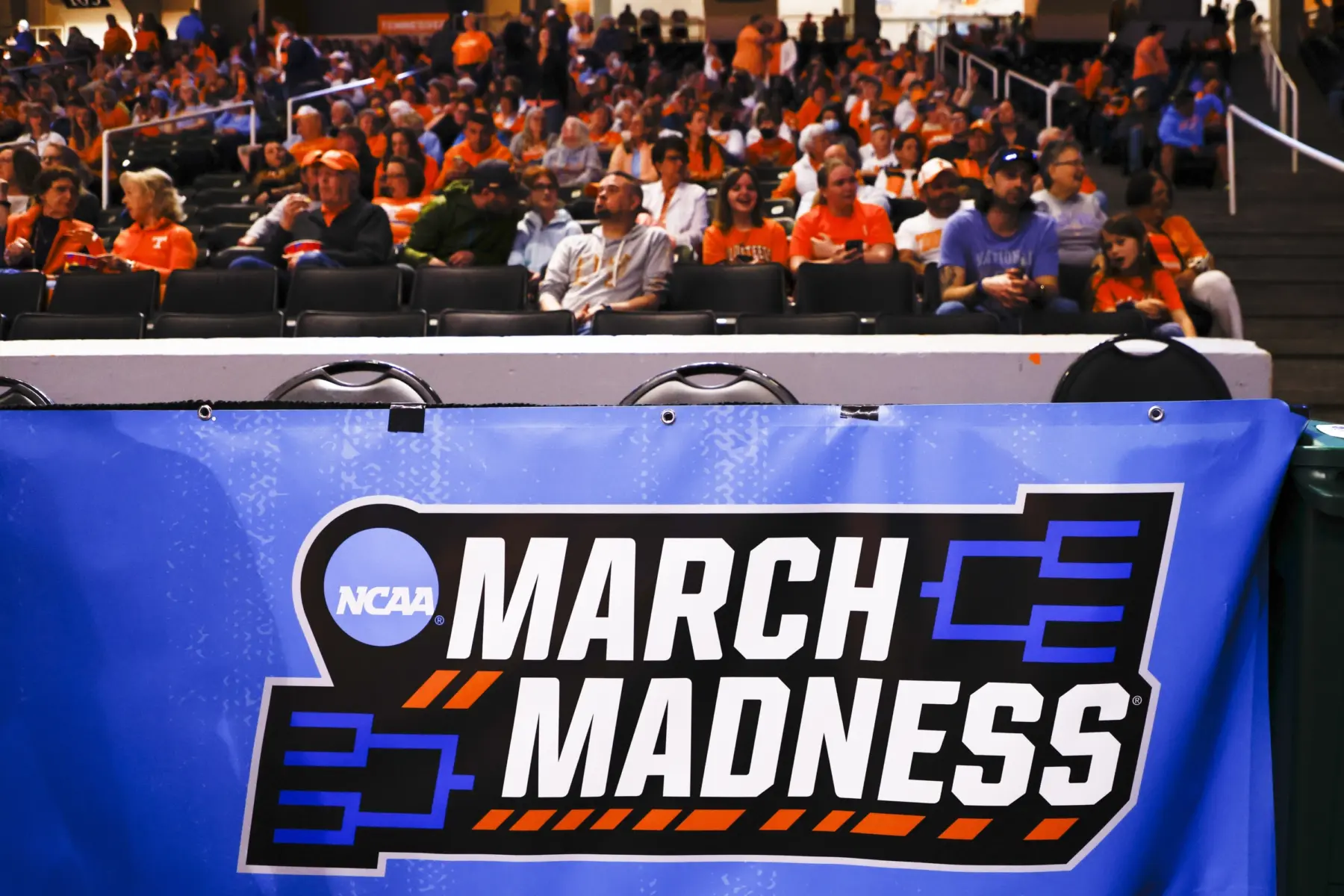A March Madness banner is seen in front of the stands as fans watch a game.