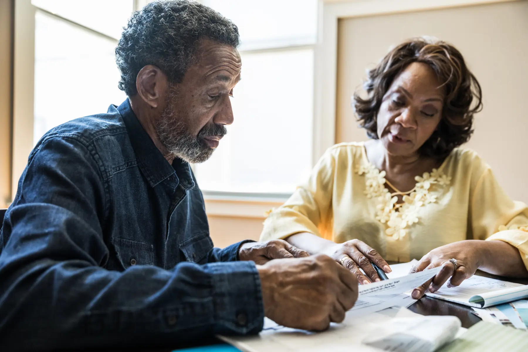 Couple sits at kitchen table looking over documents.