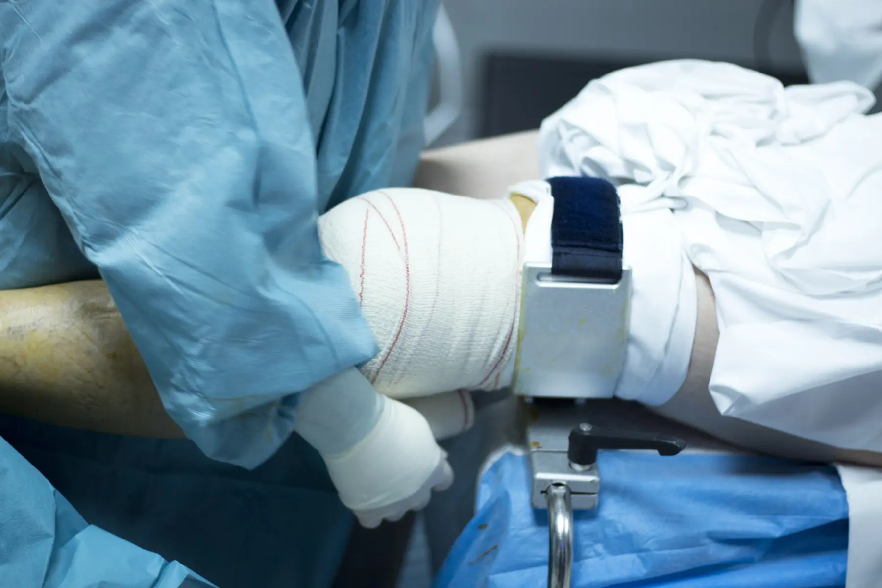 Doctor in hospital wraps a patient's knee after surgery.