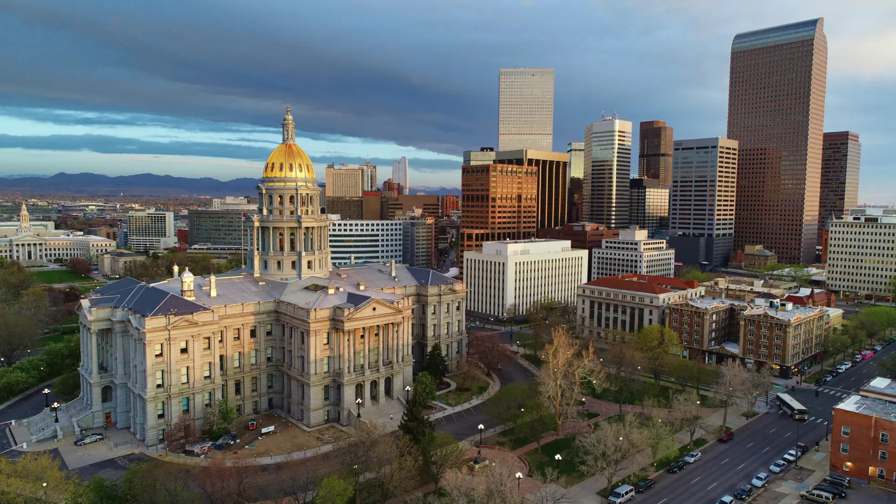 The Colorado State Capitol with its distinctive golden dome stands proudly in the foreground, surrounded by Denver's modern skyline.