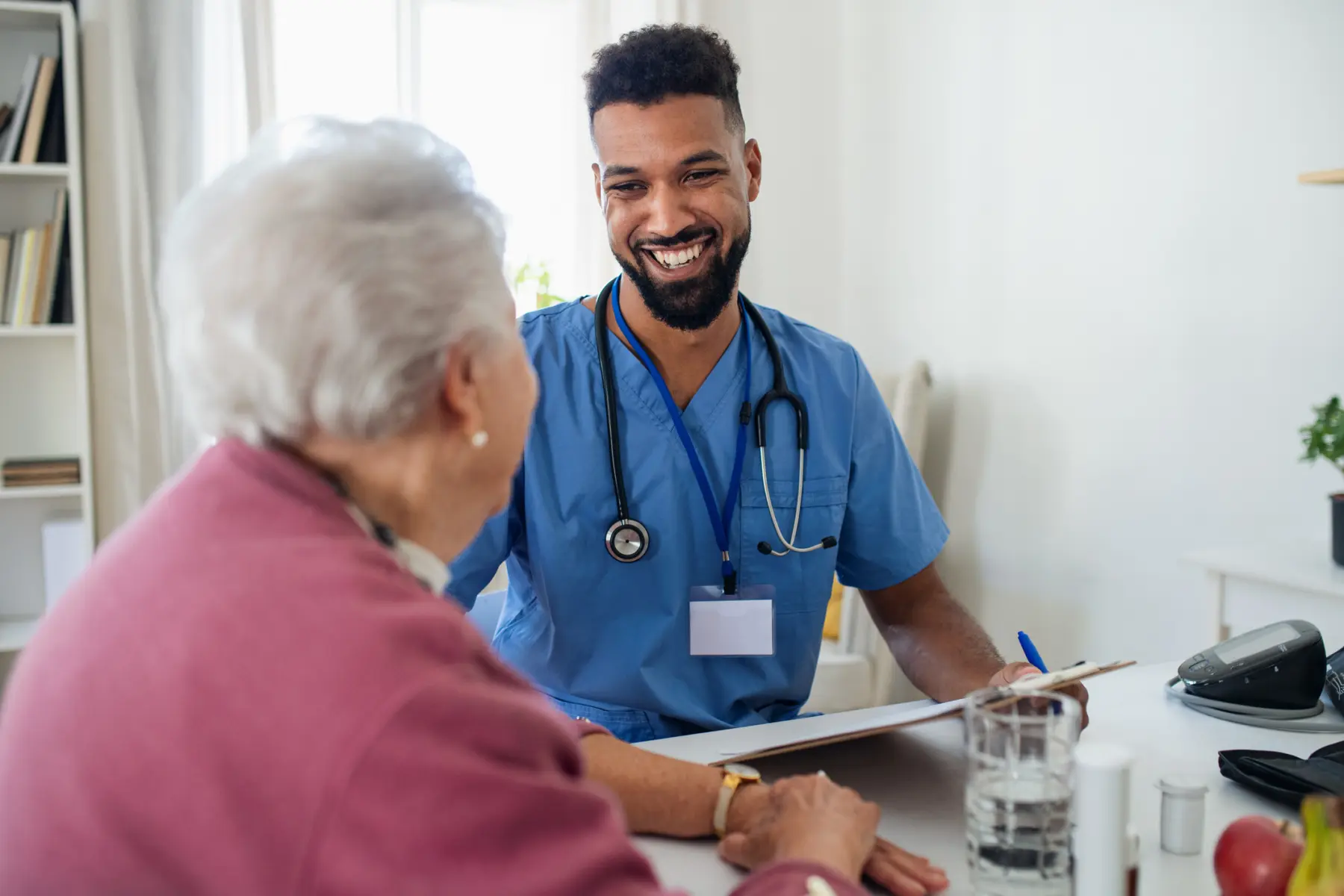 Healthcare worker visits senior woman indoors at home.