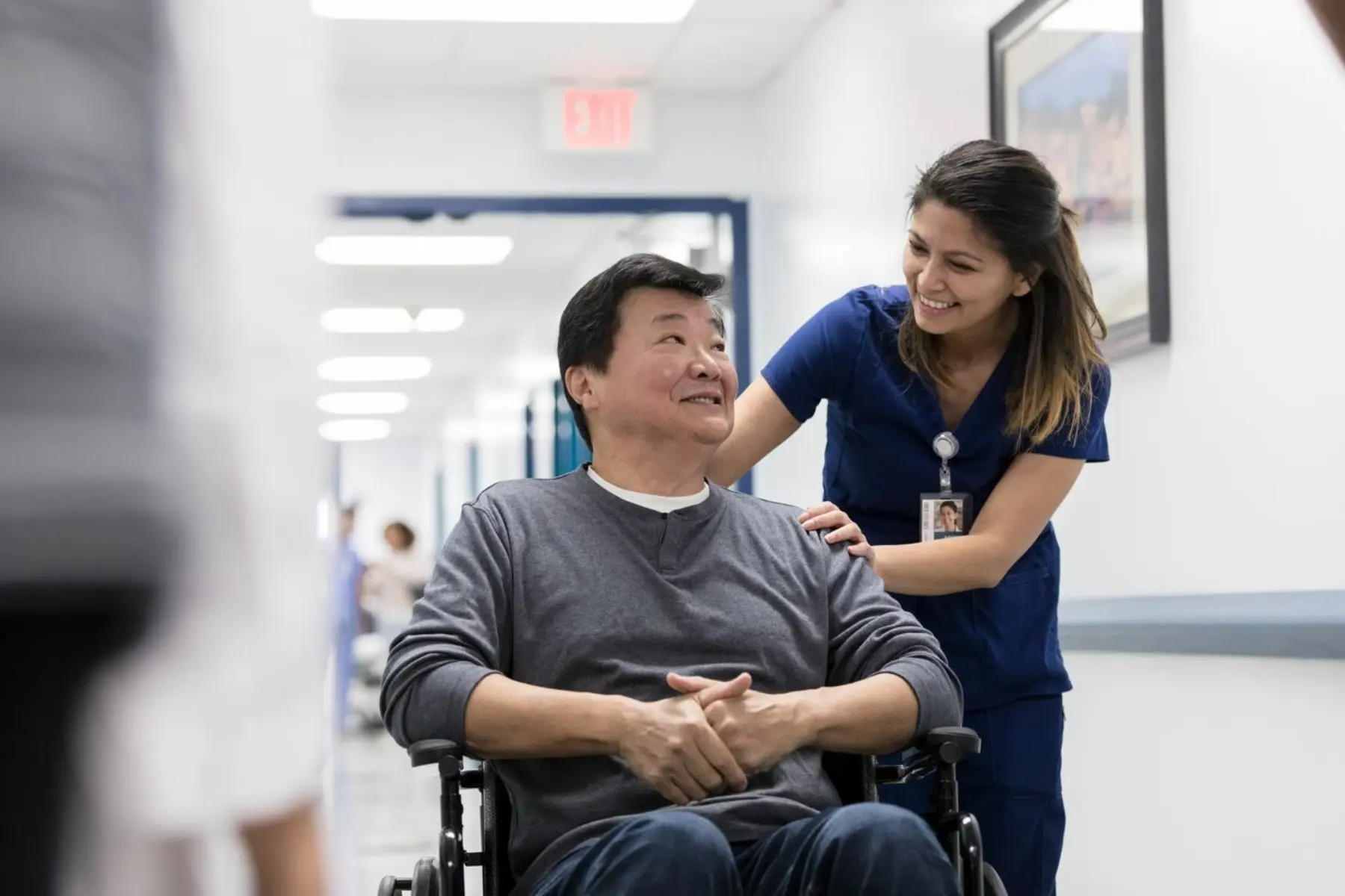 Female care provider speaking with disabled male patient in wheel chair.