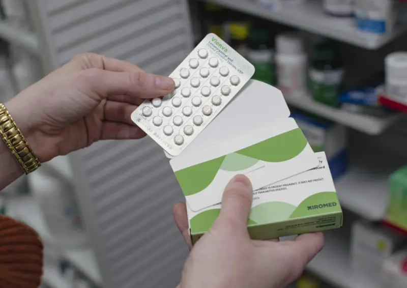 Close up image of pharmacist holding birth control packet in hands.