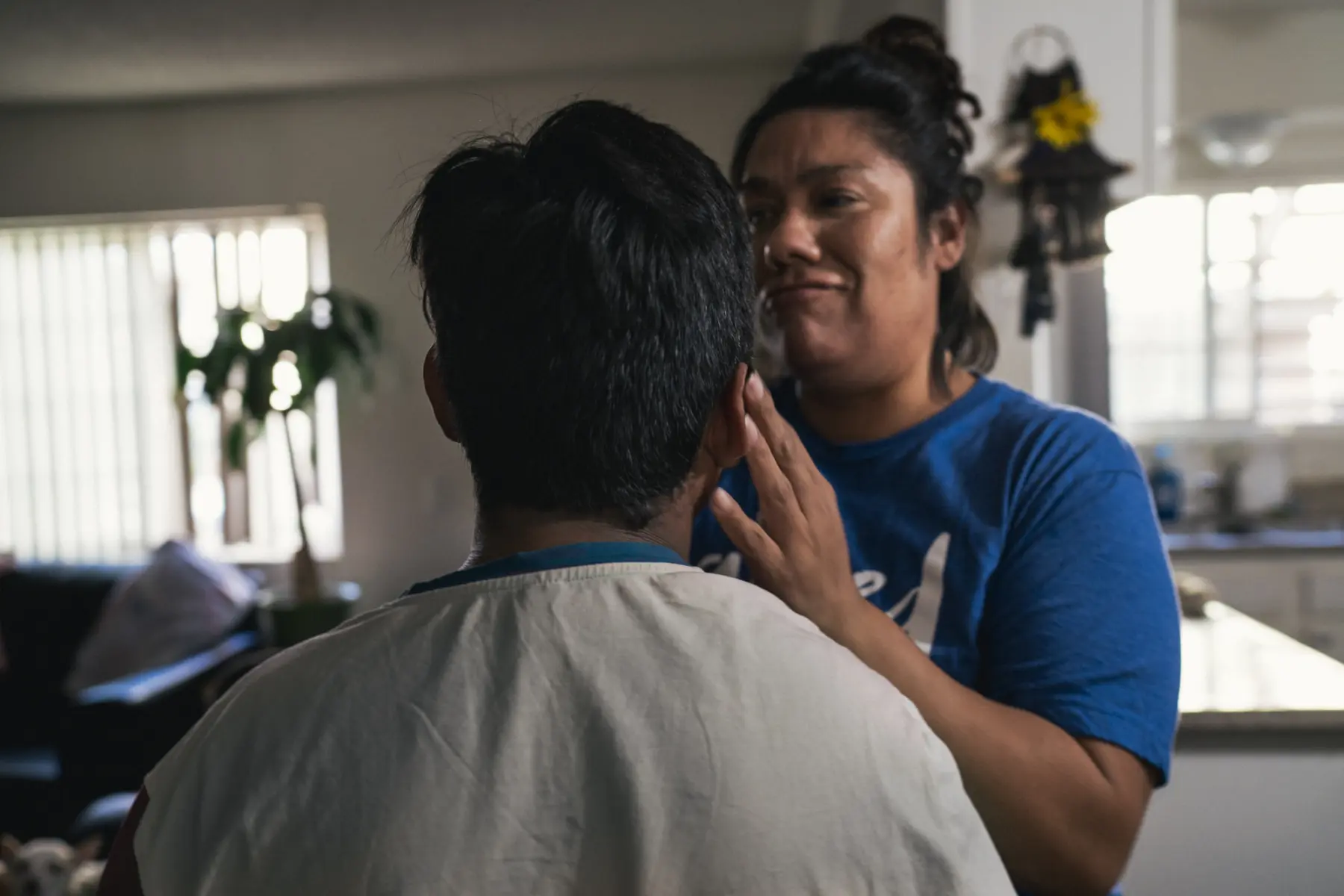 Jacob is seen from the back of his head. His mother, Melissa, stands in front of him and touches his ear. Her hand on his ear is in focus but her face and torso are out of focus.