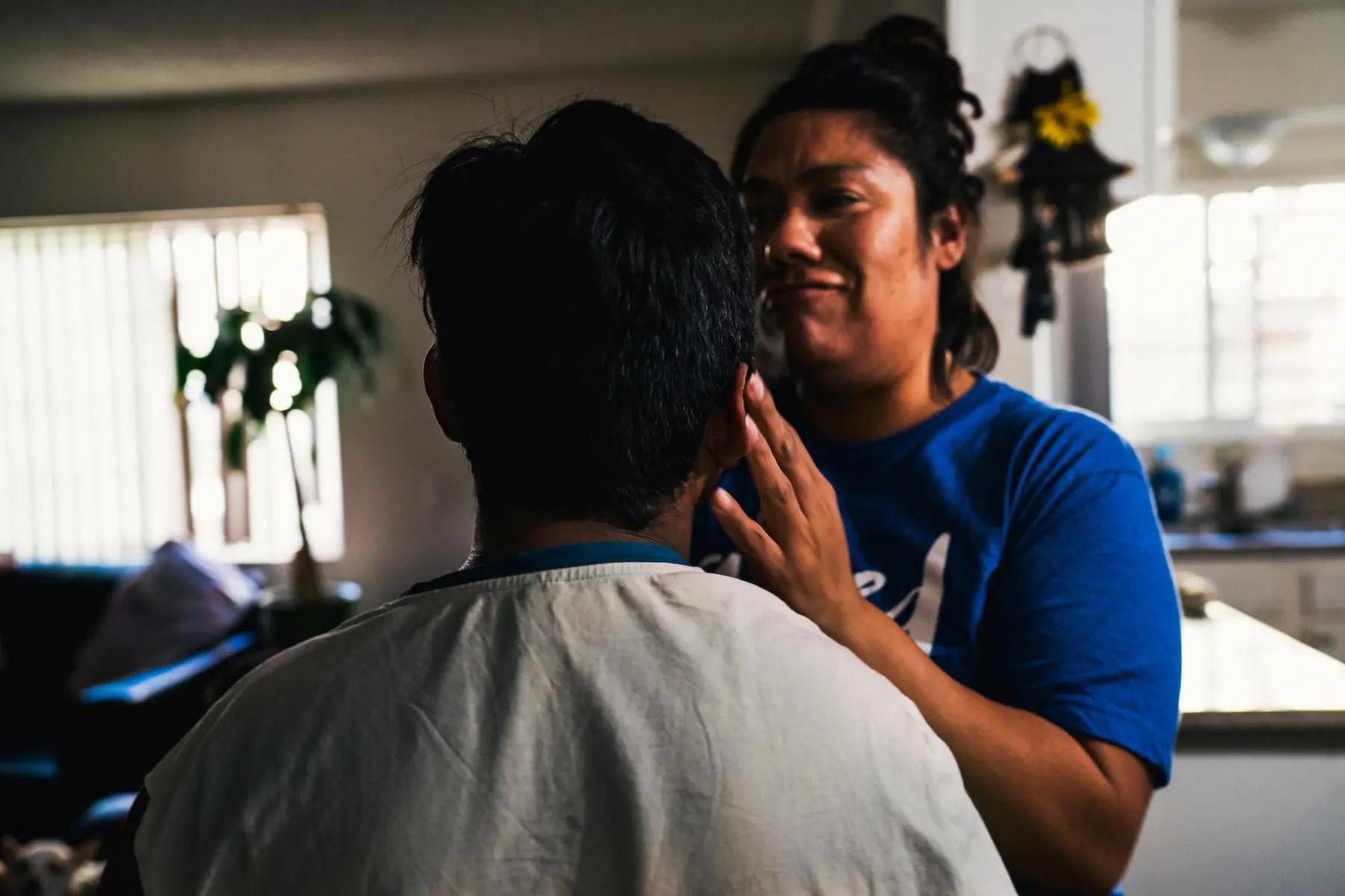Jacob is seen from the back of his head. His mother, Melissa, stands in front of him and touches his ear. Her hand on his ear is in focus but her face and torso are out of focus.